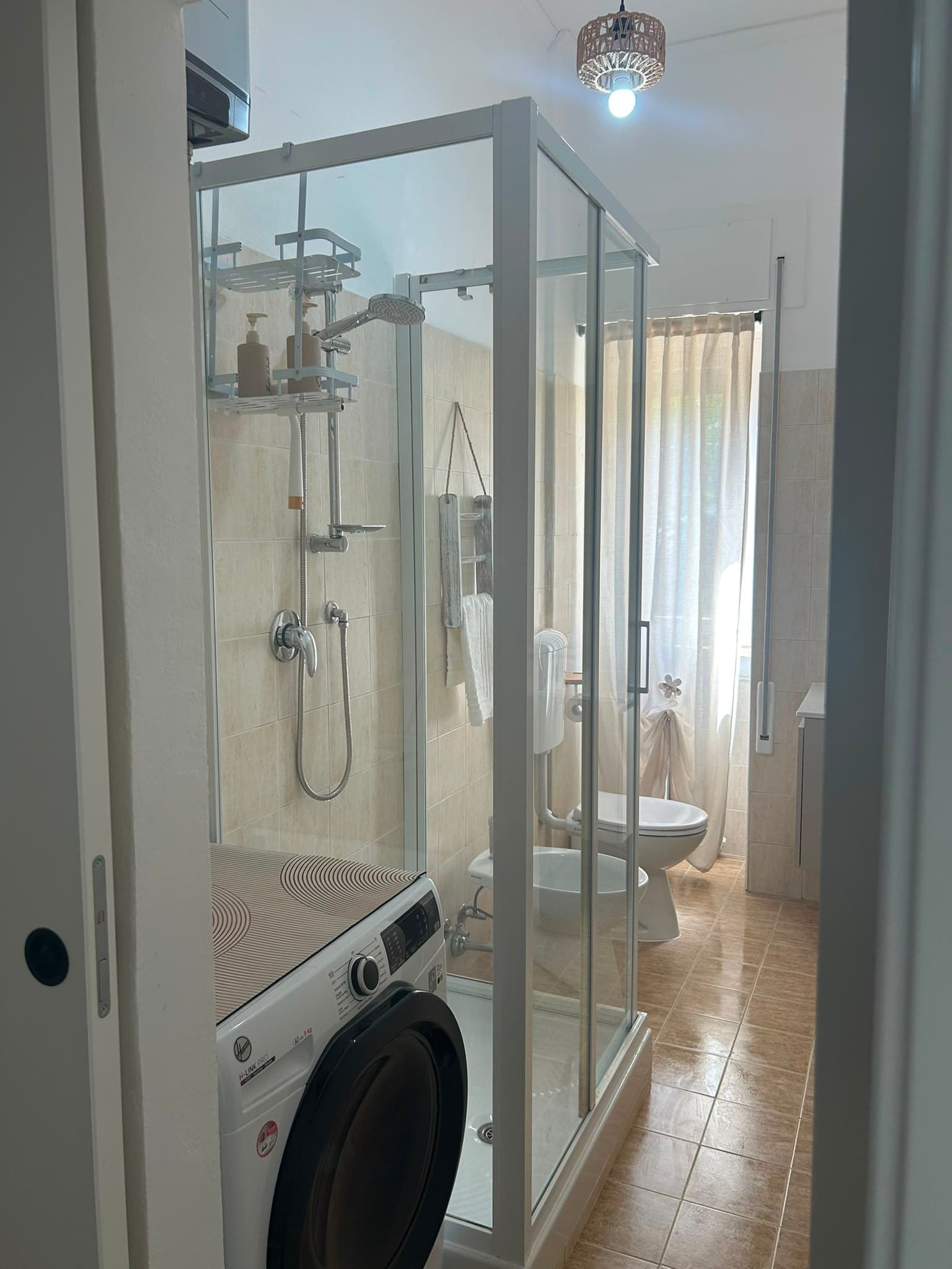 The glass-enclosed shower and the washing machine in the bathroom