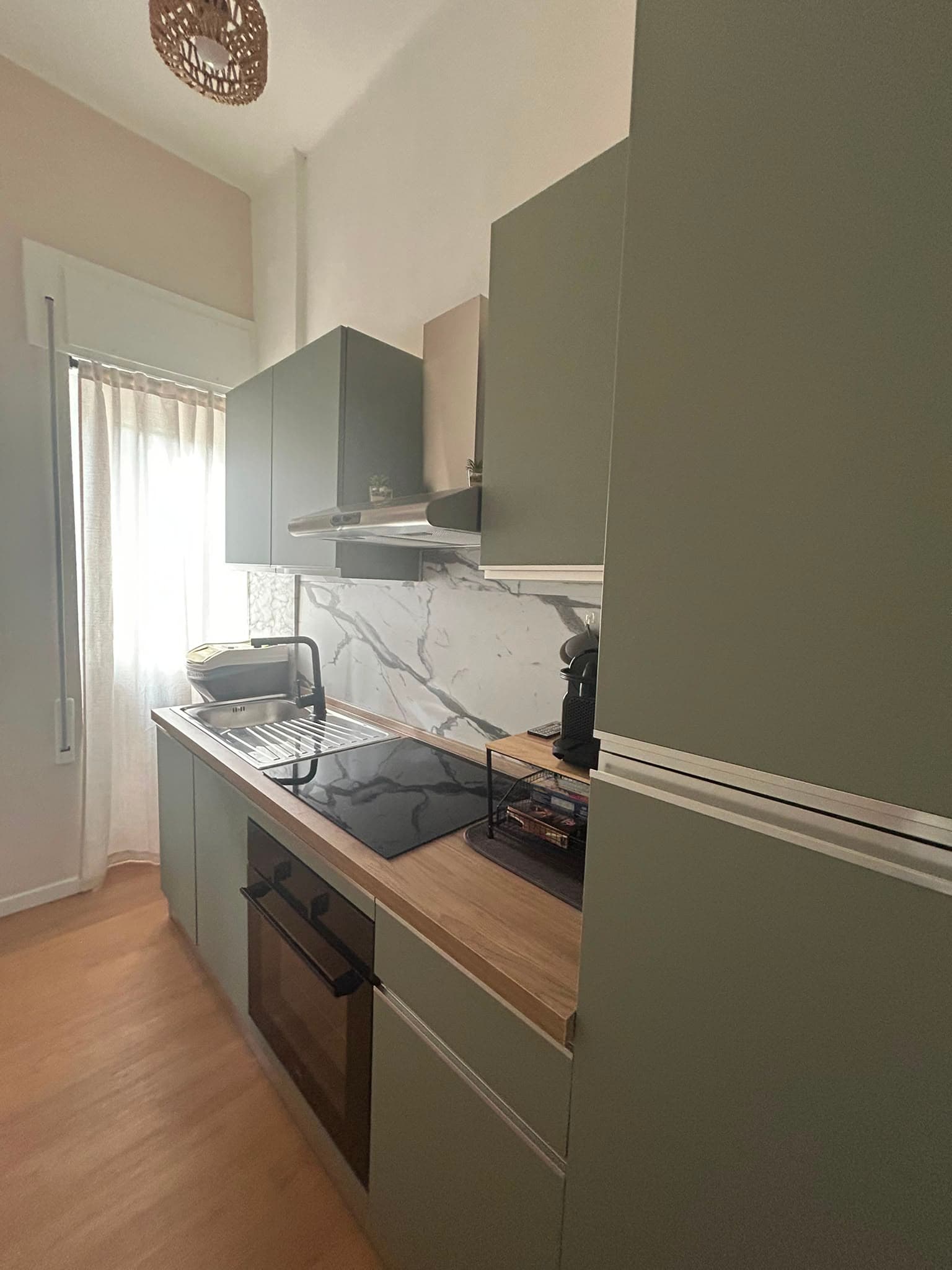 The fitted kitchen with sage-green units and a marble worktop