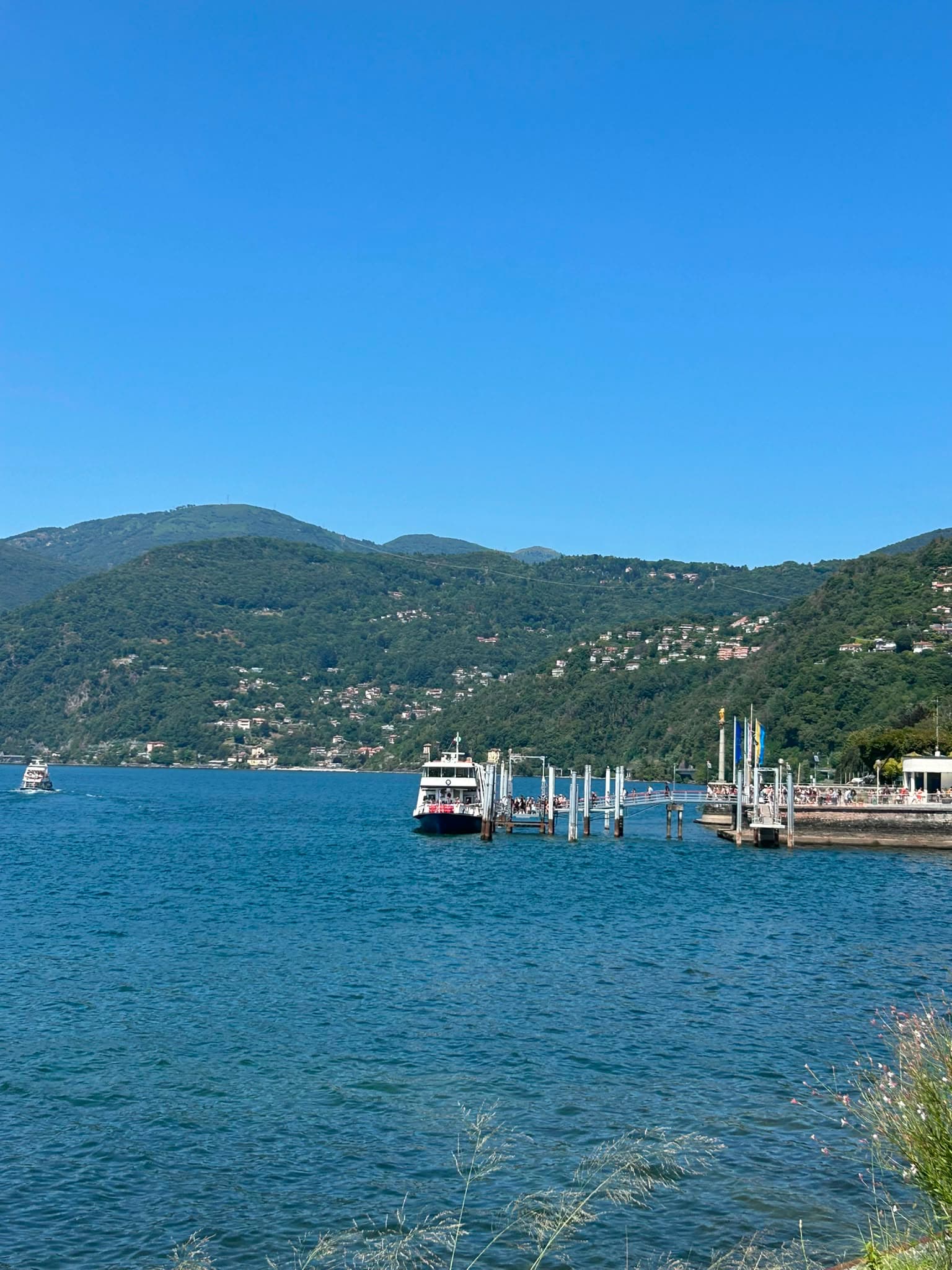 Lake Maggiore in summer with the ferry pier and green hills